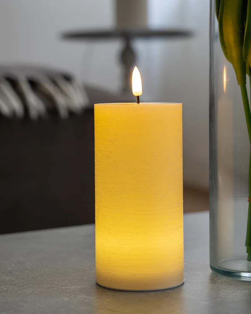 Bougie LED en cire sur une table basse avec un bouquet de tulipes