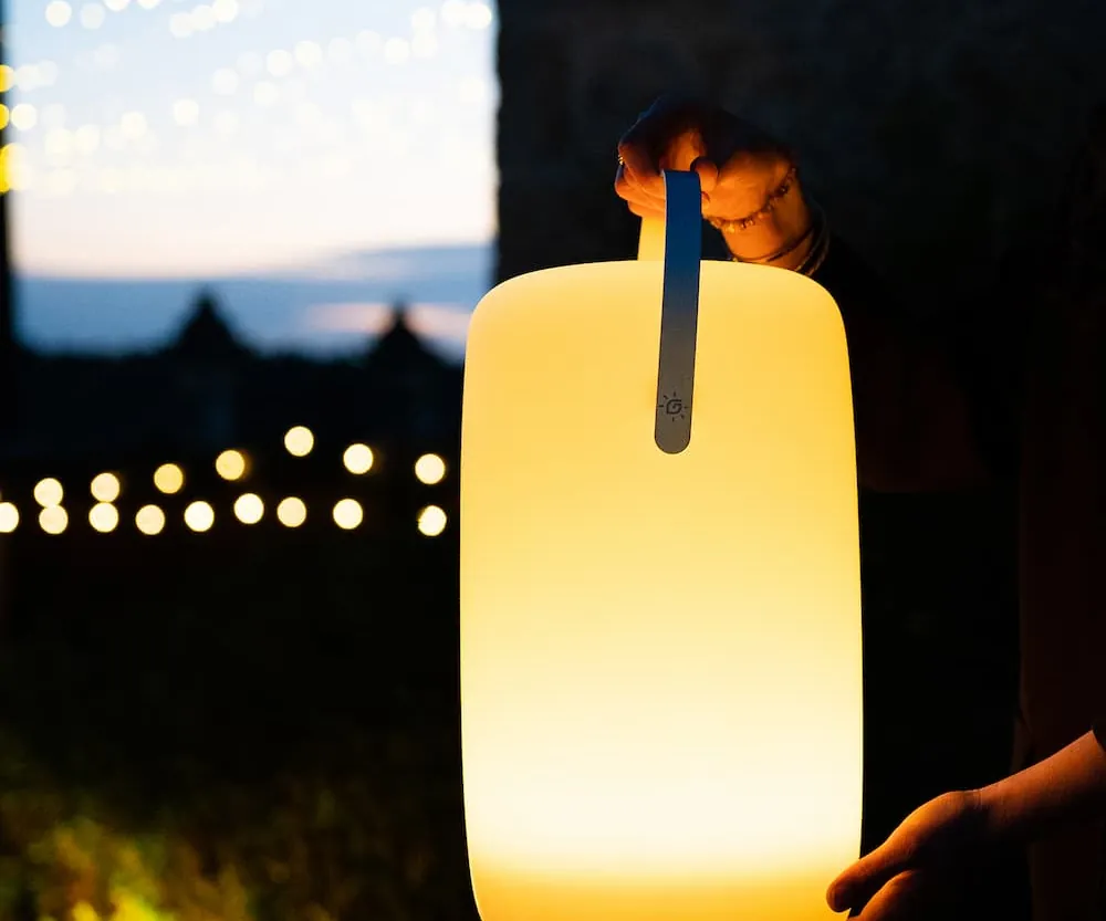 Guirled Nomade solar lamp in de hand bij zonsondergang
